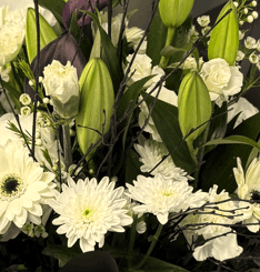 A close up section of flowers in white with black birch twigs and wrapping